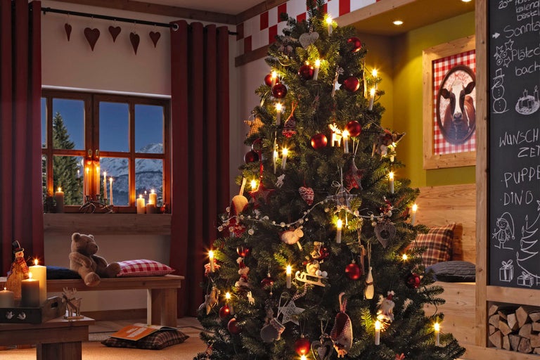 Sapin de Noël décoré pour les fêtes avec des lumières et des décorations dans un salon confortable.