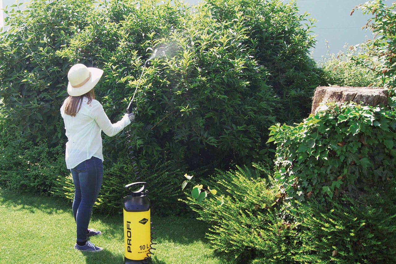 Une femme utilise un pulvérisateur de jardin pour l'entretien des plantes