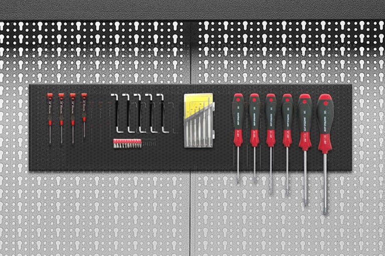 Assortiment de tournevis divers, rangés sur un panneau mural pour outils.