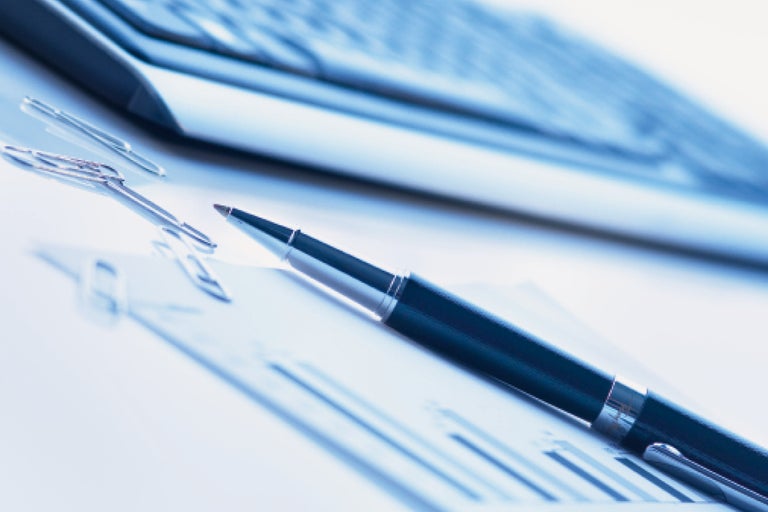 Stylo et trombones sur diagramme à côté d'un ordinateur portable