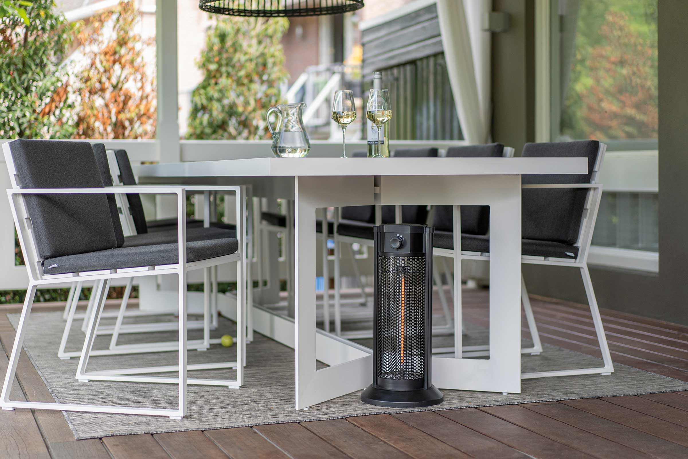 Terrassenszene mit weissem Gartentisch, Stühlen und schwarzem Heizstrahler für eine gemütliche Atmosphäre im Freien