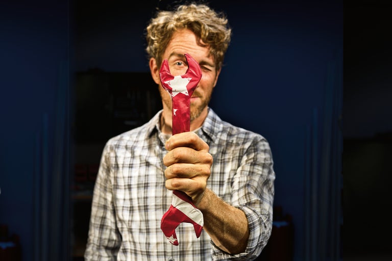 Mann hält einen Schraubenschlüssel mit einer Sternverzierung vor sein Gesicht