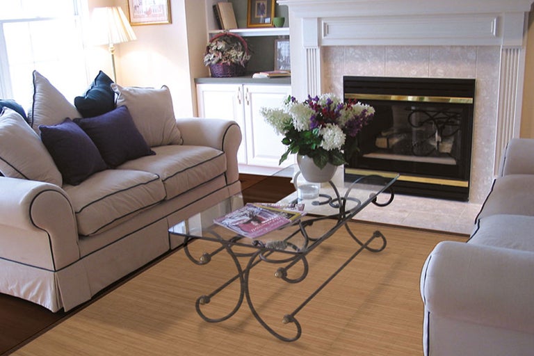 Salon avec canapé, table basse avec plateau en verre et cheminée.