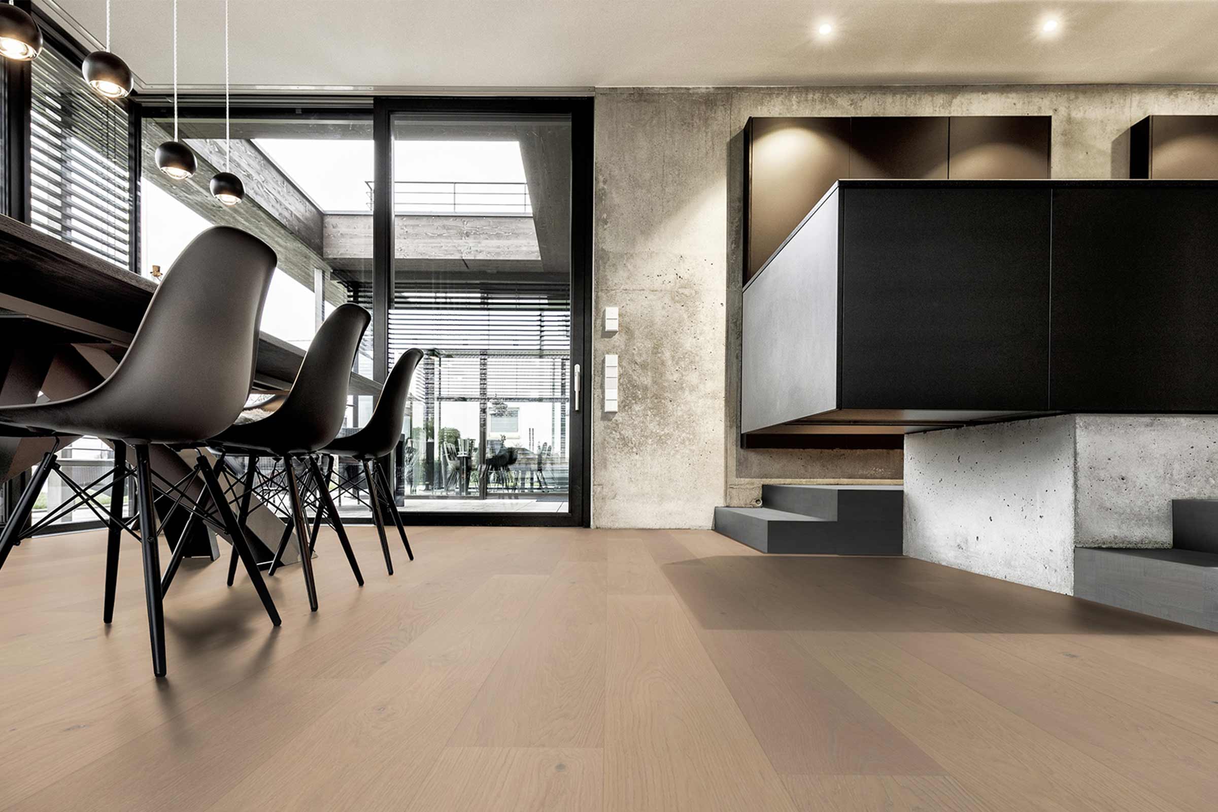 Plancher en bois clair dans une pièce moderne avec table à manger et coin cuisine.