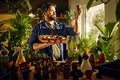 Un homme observe un plant dans un pot de culture devant une fenêtre avec des plantes. Un homme observe un plant dans un pot de culture devant une fenêtre avec des plantes.