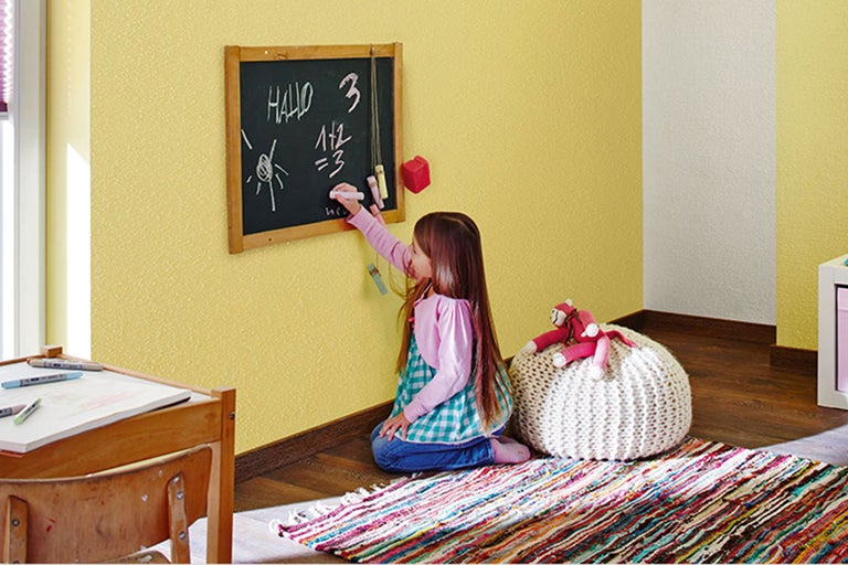 Fille écrit à la craie sur un tableau noir dans la chambre d'enfant