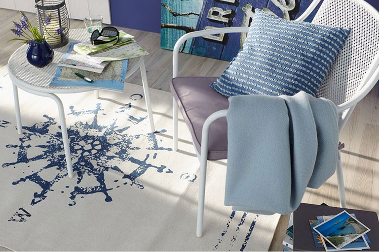 Ambiance de vie décorative avec chaise blanche, table d'appoint, tapis à motif de boussole et accessoires