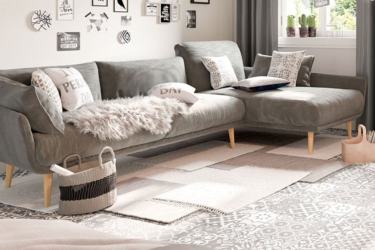 Salon avec canapé d'angle gris, coussins et tapis sur un sol à motifs