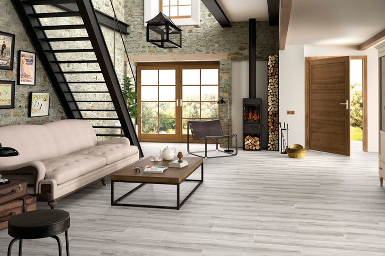 Salon avec escalier, poêle à bois et plancher en bois à l'aspect bois