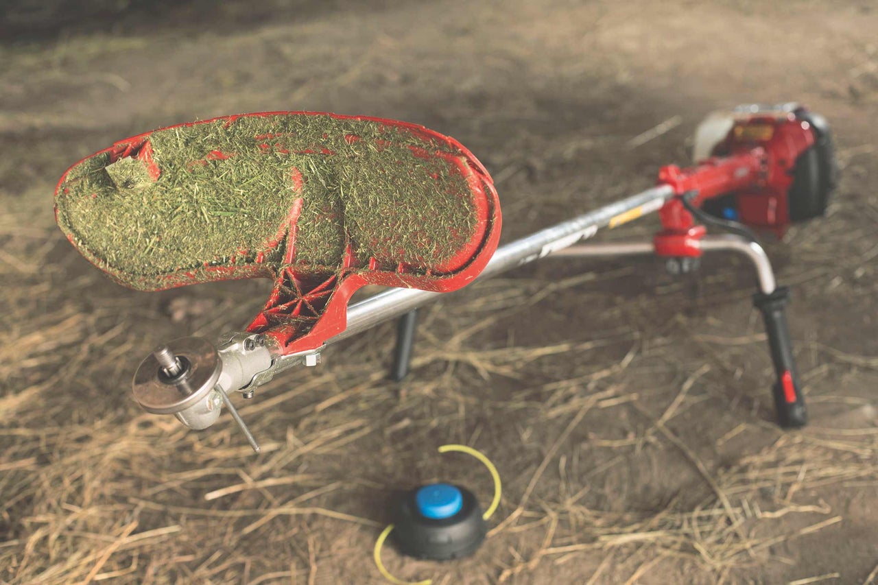 Rasentrimmer mit Grasschutz und Trimmerfaden auf dem Boden