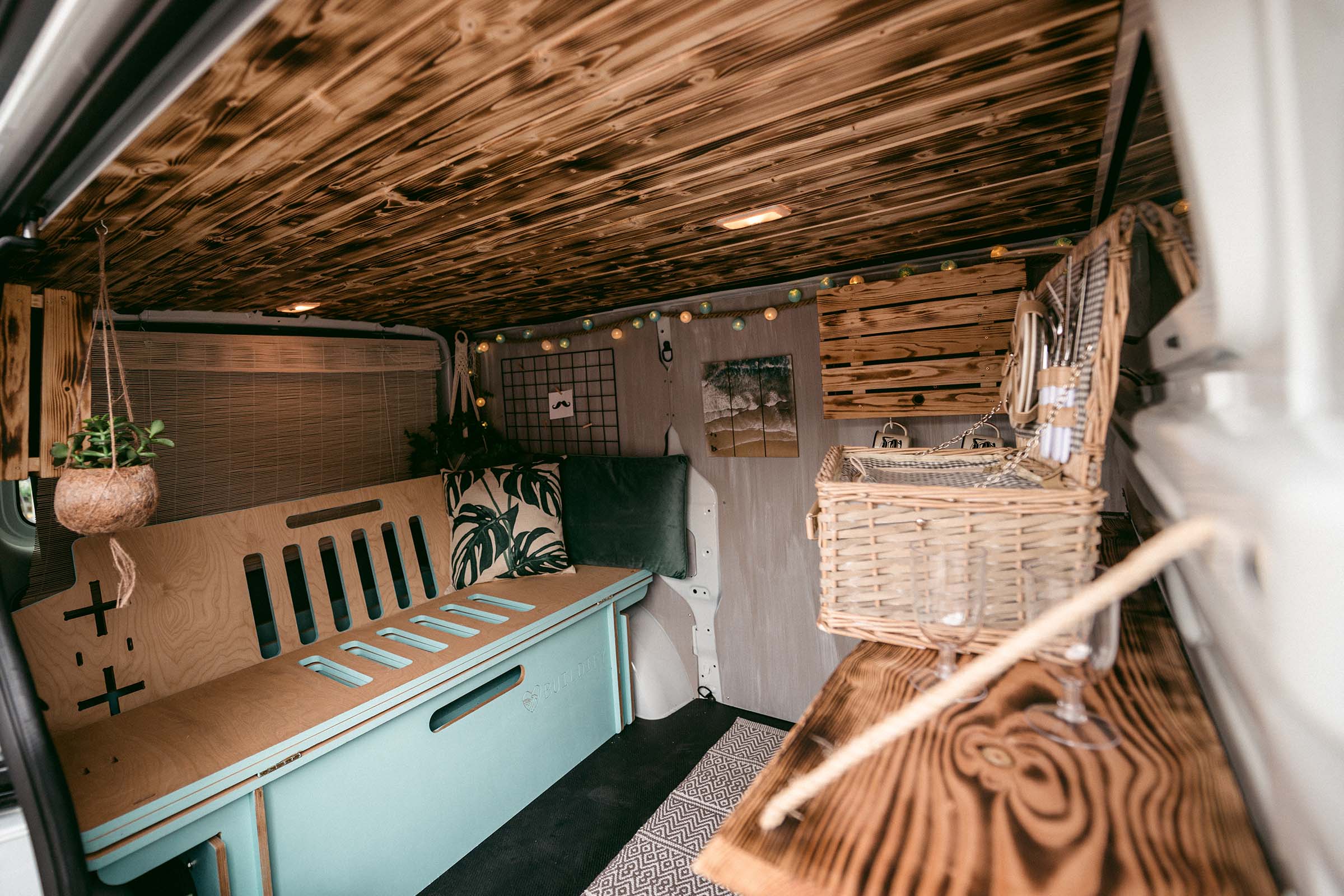 Intérieur d'un fourgon transformé avec plafond en bois, banquette et éléments décoratifs pour l'aménagement