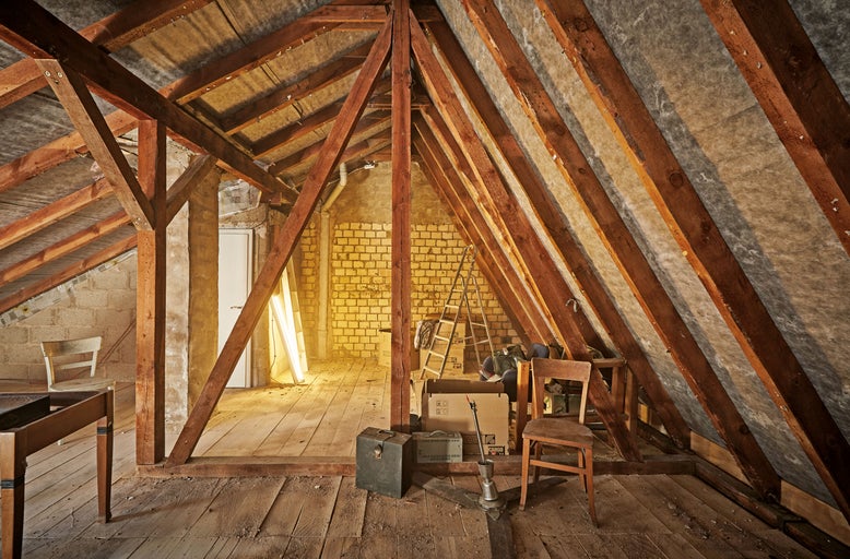 Grenier avec poutres en bois, isolation de toit et objets stockés