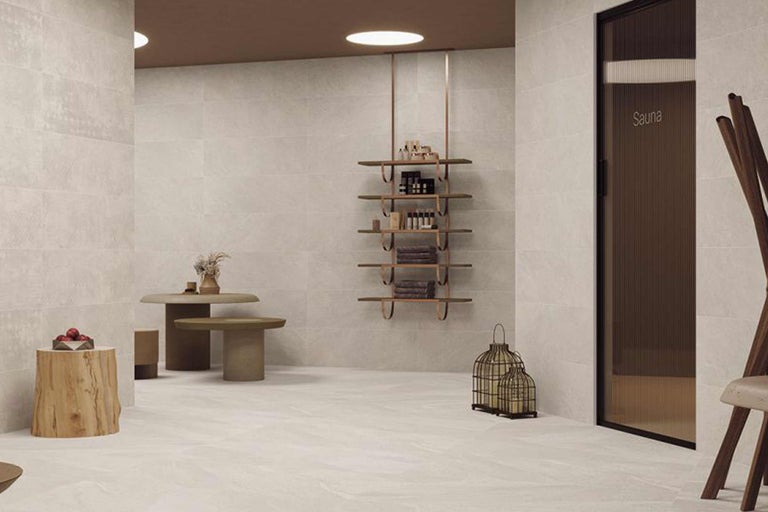 Heller Raum mit Fliesenboden, Holzhocker, Tisch, Regal und Sauna
