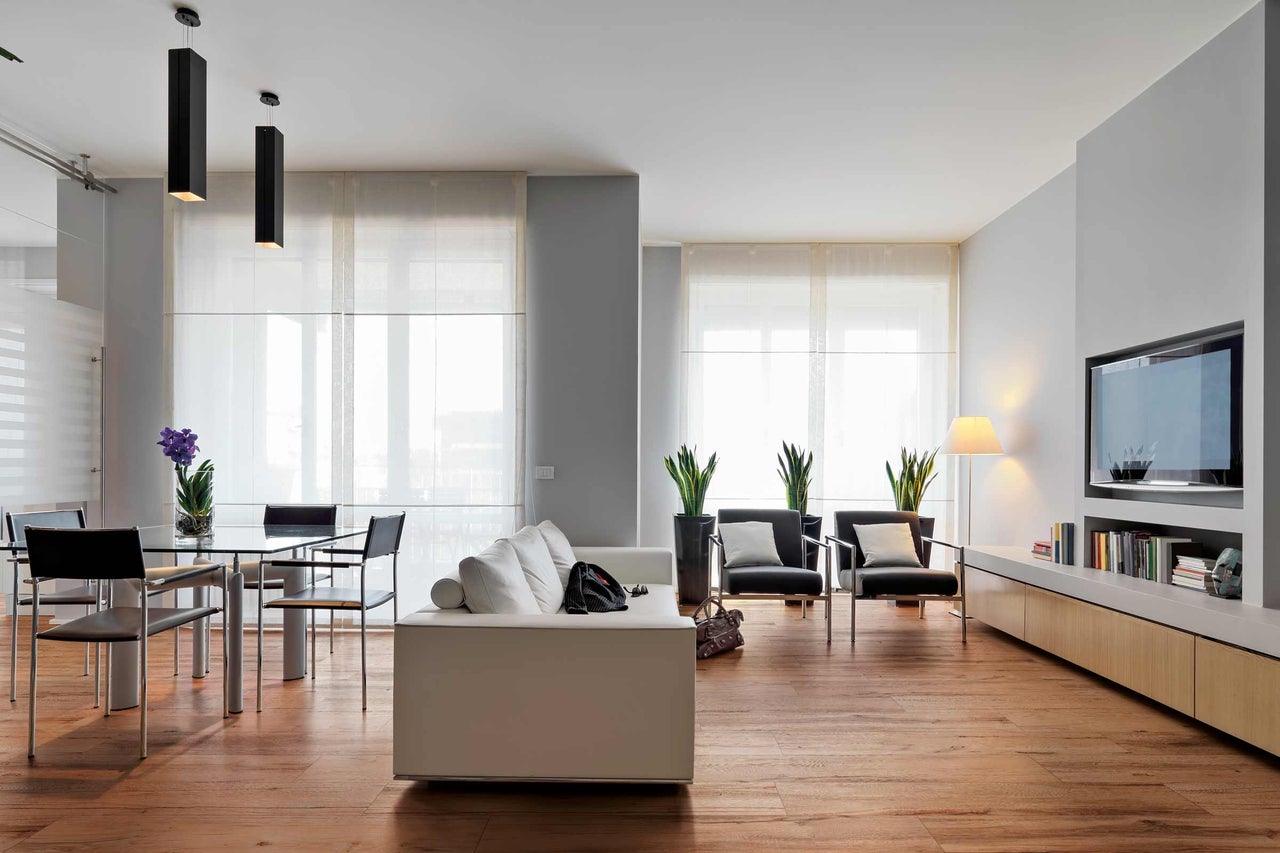 Salon lumineux avec canapé, fauteuils, table à manger et télévision