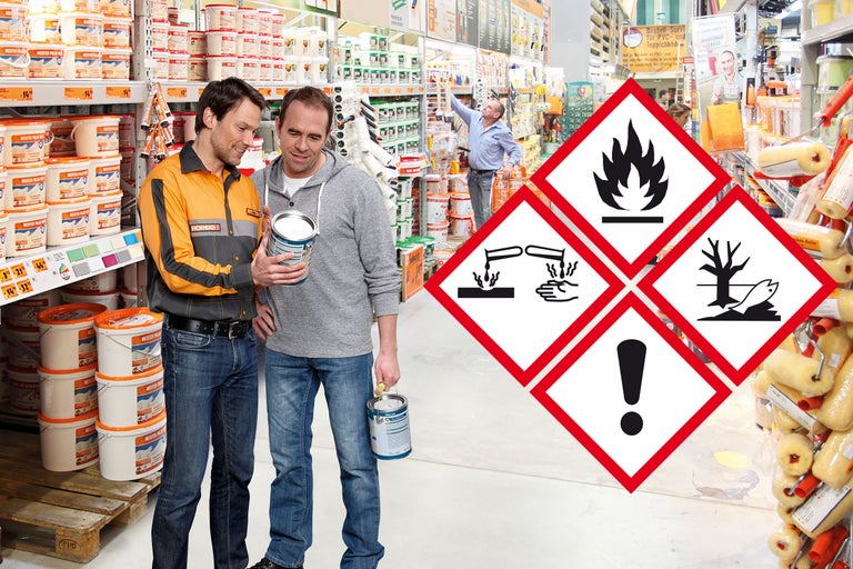 Clients choisissant une peinture au magasin Hornbach, symboles de danger : inflammable, corrosif, irritant, dangereux pour l'environnement.