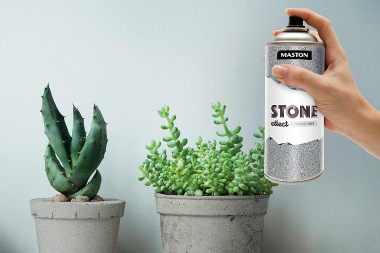Eine Dose Steineffekt-Spray wird neben zwei Topfpflanzen gehalten