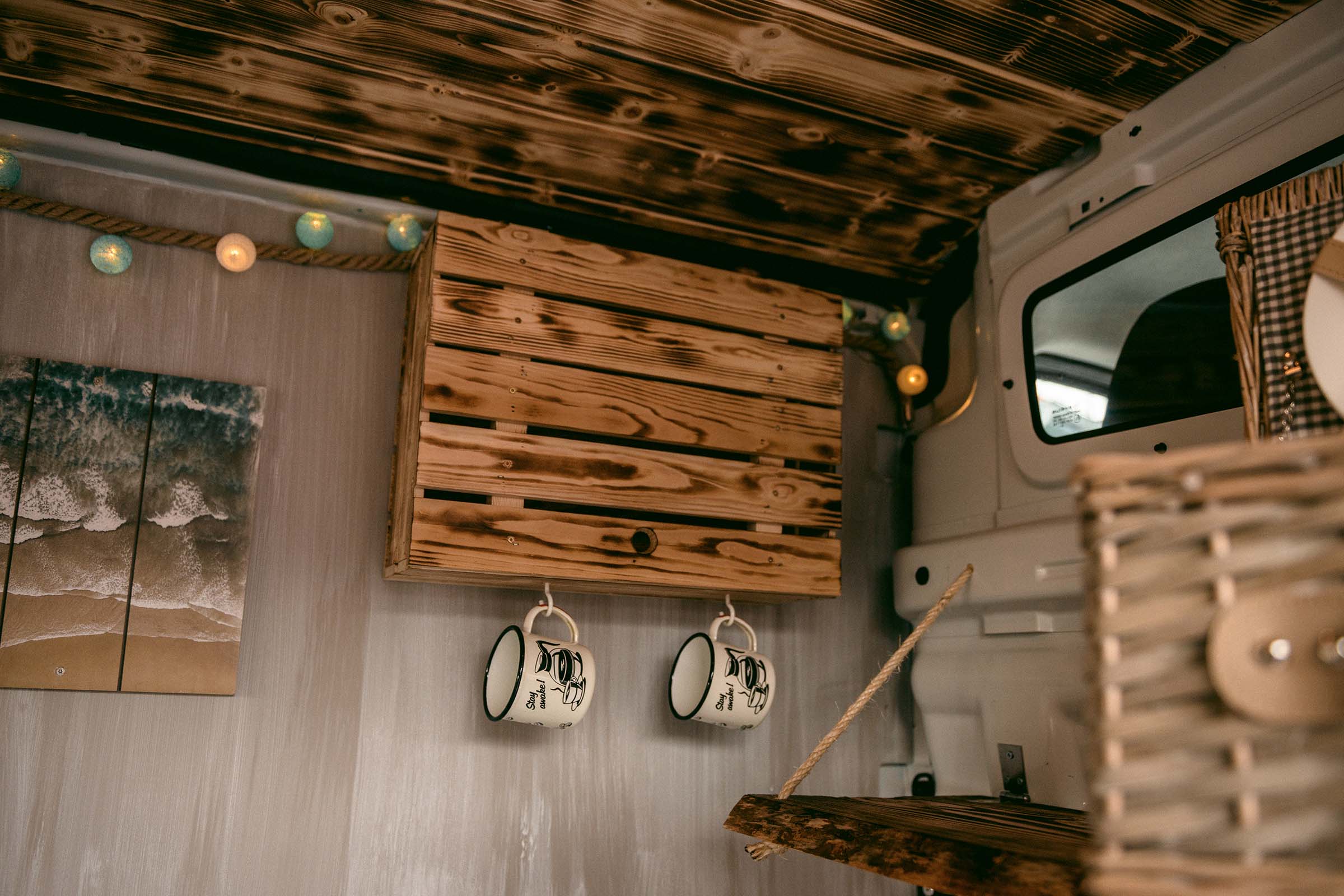 Intérieur d'un camping-car avec plafond en bois, tableau, étagère en bois et tasses