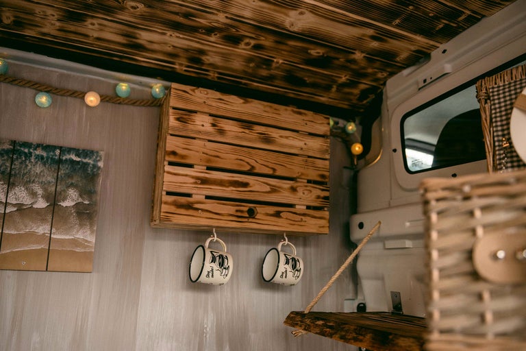 Innenraum eines Wohnmobils mit Holzdecke, Wandbild, Holzregal und Tassen
