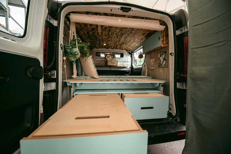 Innenraum eines umgebauten Kastenwagens mit Holzausstattung, Bett und Stauraumlösungen