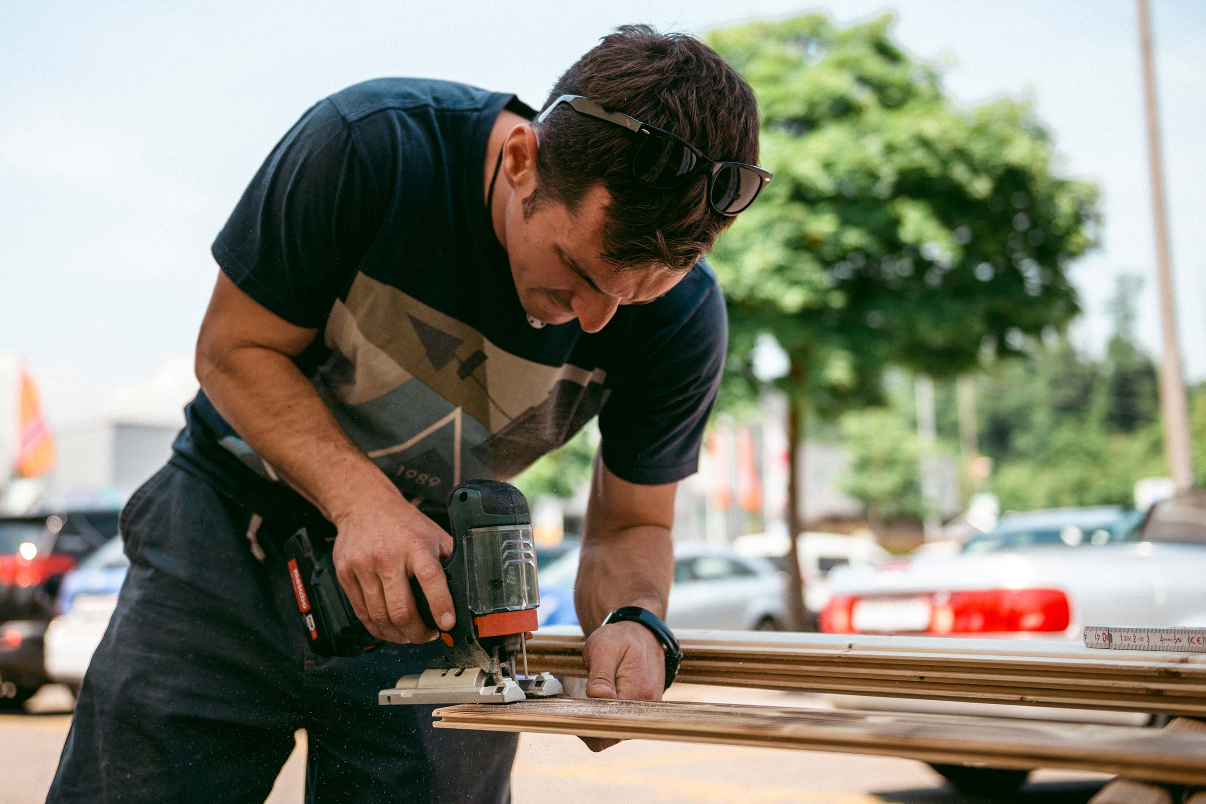 Homme coupant un plancher en bois avec une scie sauteuse