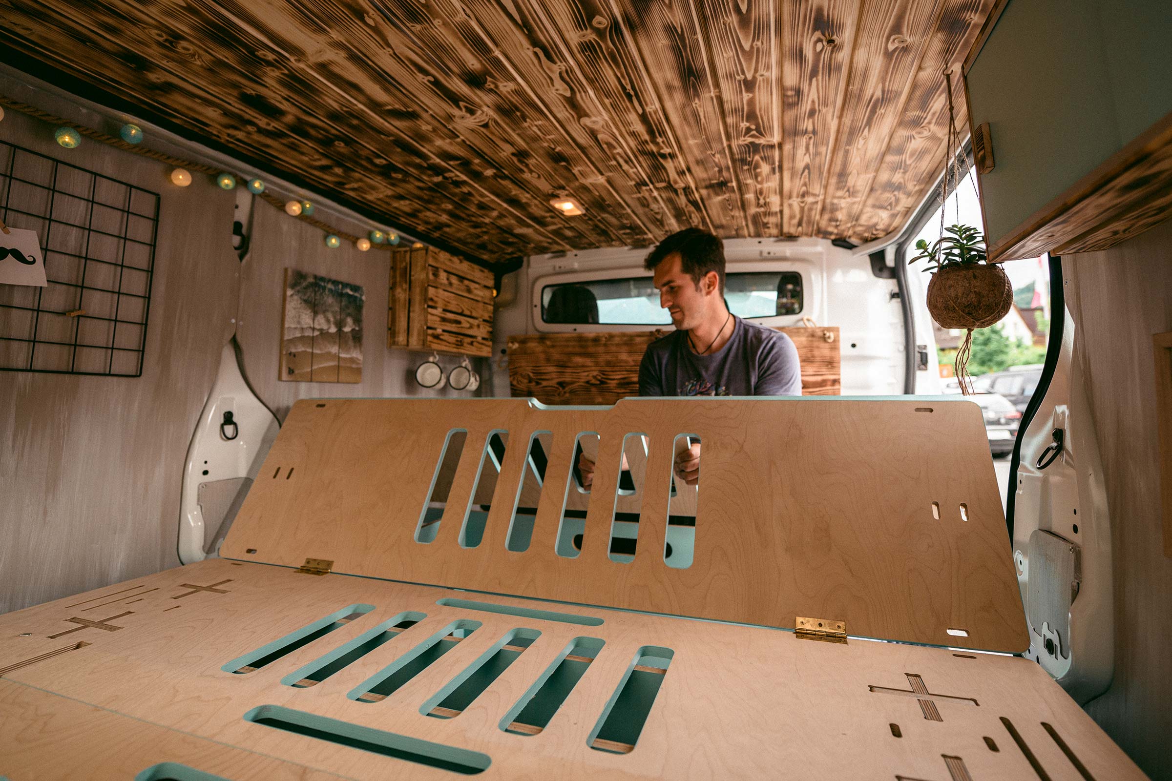 Intérieur d'un fourgon aménagé avec lit en bois et habillage de plafond