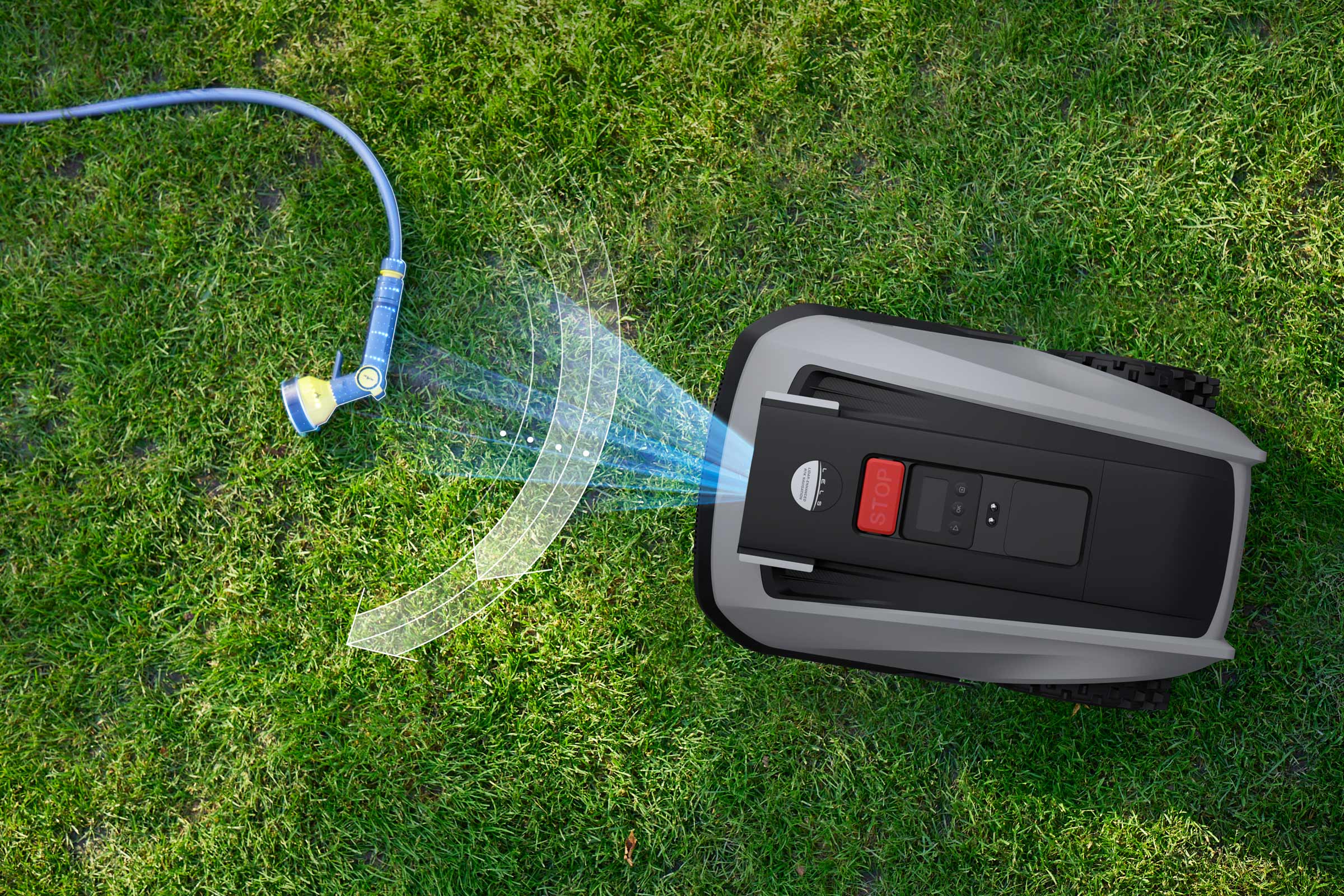 Aufsicht eines Rasenmähroboters auf Rasen, der mit einer Gartenschlauchbrause bewässert wird.