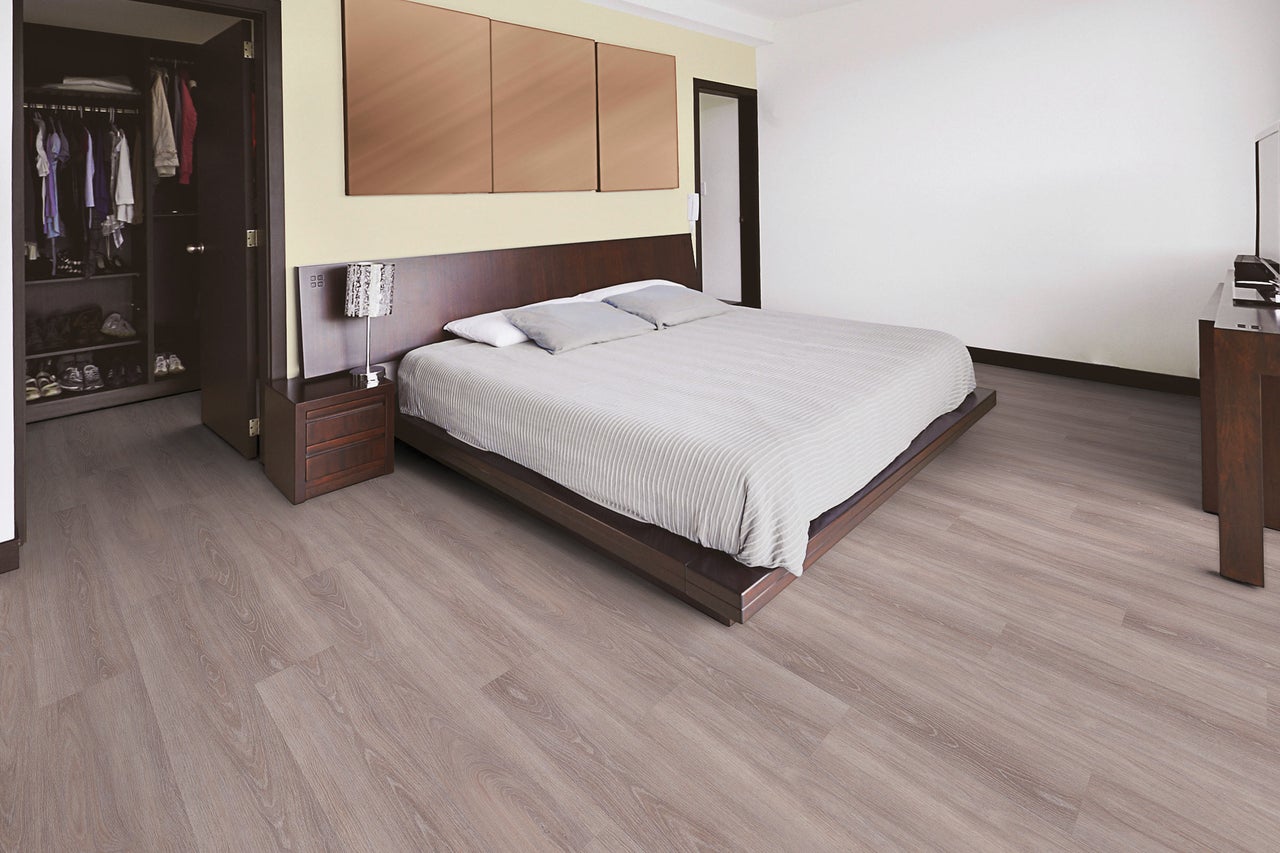 Heller Schlafraum mit Bett, Schrank und Laminatboden.