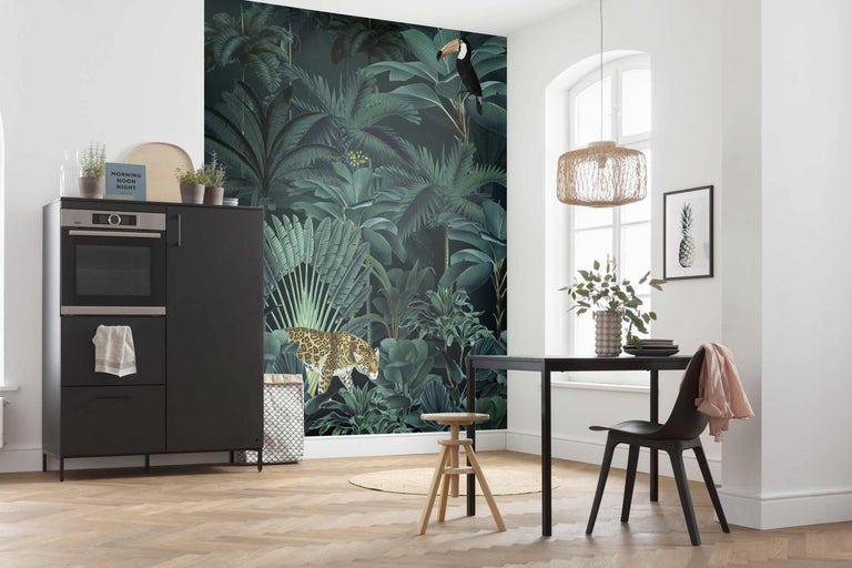 Salle à manger lumineuse avec papier peint jungle, comptoir de cuisine, table et chaises.