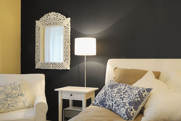 Helles Schlafzimmer mit Bett, Nachttisch, Lampe und Spiegel