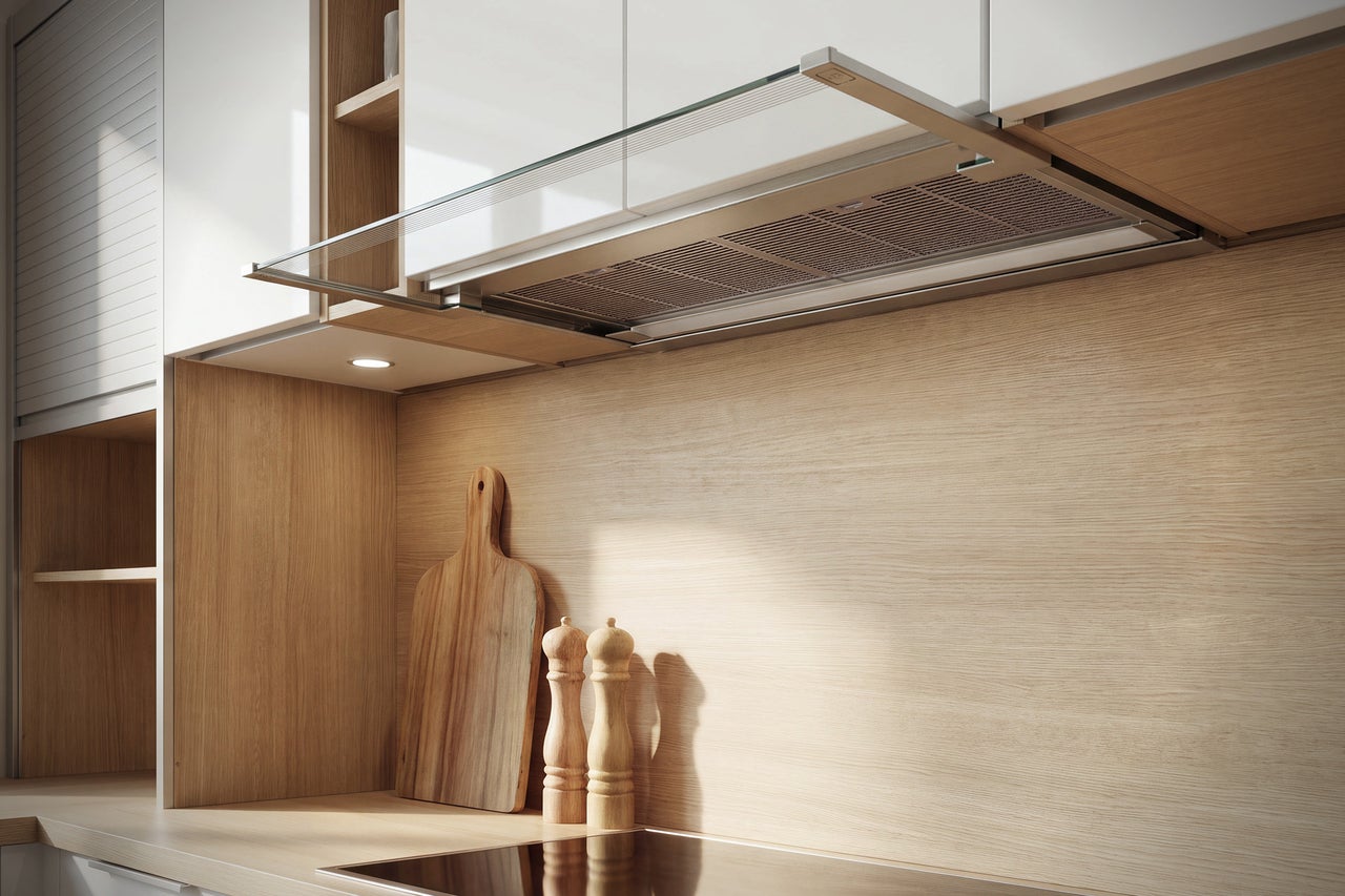 Hotte aspirante moderne sous un meuble de cuisine, dans une cuisine avec surfaces en bois et plaque de cuisson.