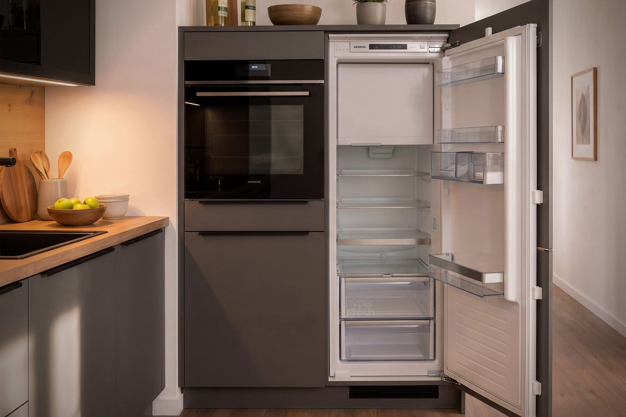 Moderne Einbauküchenzeile mit integriertem Siemens Backofen und Siemens Kühlschrank in einer grauen Schrankfront.