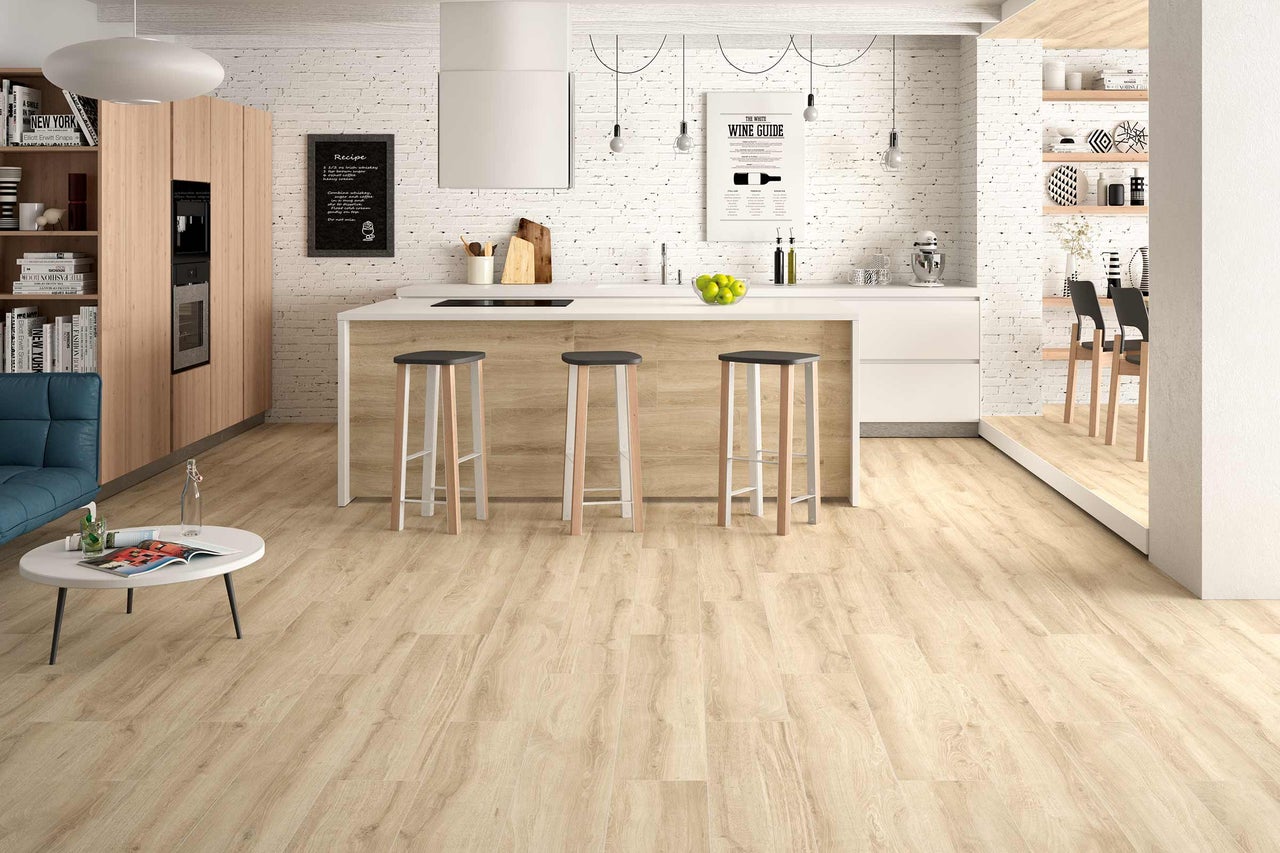 Helle, moderne Küche mit Holzboden, Kochinsel, Barhockern und dekorativen Elementen für ein einladendes Ambiente.