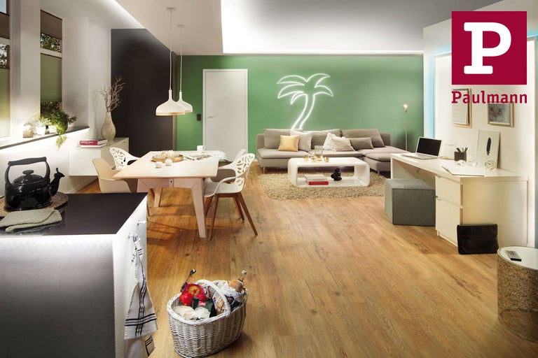 Heller Wohnraum mit Esstisch, Sofa und Arbeitsbereich.