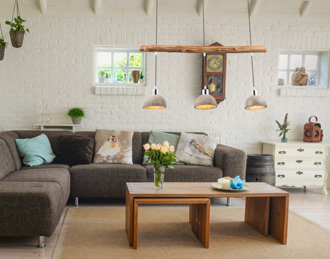 Wohnzimmer mit Ecksofa, Couchtisch, Kommode und Hängelampe im Landhausstil