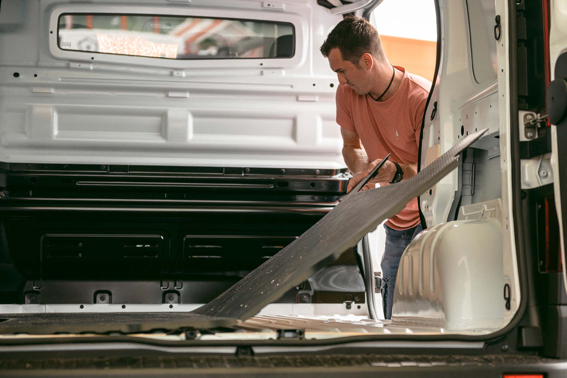Un homme installe un plancher dans une camionnette.