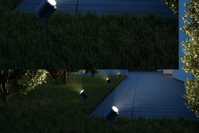 Szene mit Rasenfläche und mehreren Gartenstrahlern, die einen Weg beleuchten.