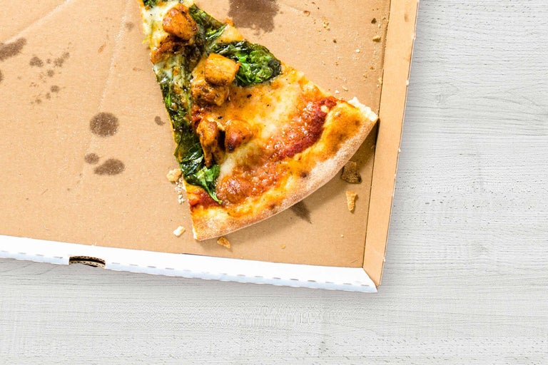 Une part de pizza aux épinards et au poulet dans une boîte à pizza