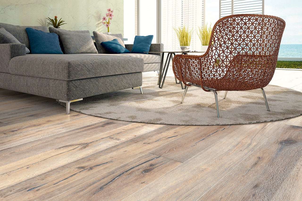 Wohnzimmer mit Sofa, Tisch und einem braunen Korbsessel auf Holzboden
