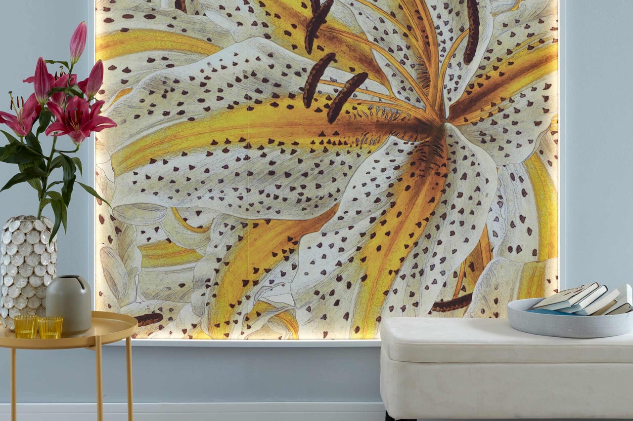 Dekoratives beleuchtetes Wandbild mit Blumenmotiv in einem Wohnraum, ergänzt durch eine Vase mit frischen Blumen und einen Hocker.