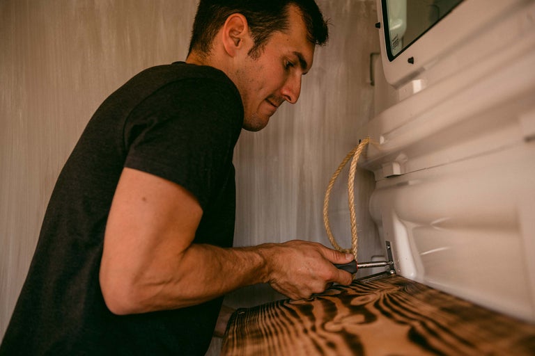 Mann schraubt Holzbrett im Innenraum fest