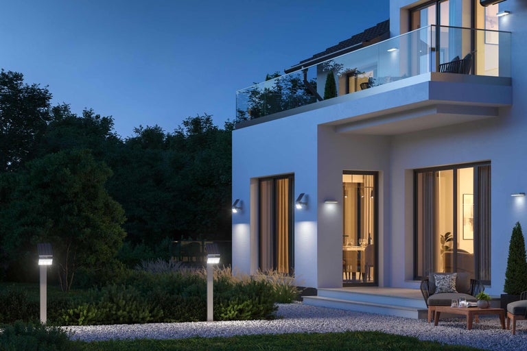 Beleuchtetes Haus mit Garten in der Nacht mit Solarleuchten und Wandleuchten