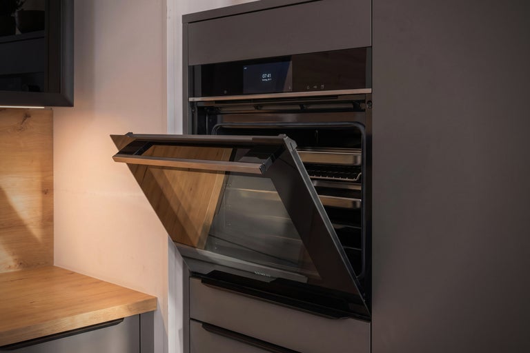 Einbau Backofen von Siemens mit offener Klapptür in einer modernen Einbauküche mit Holzoberflächen.