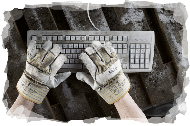 Eine Person tippt mit Arbeitshandschuhen auf einer Computertastatur.