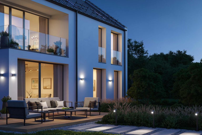 Aussenansicht eines modernen Hauses mit Gartenmöbeln und Aussenbeleuchtung am Abend