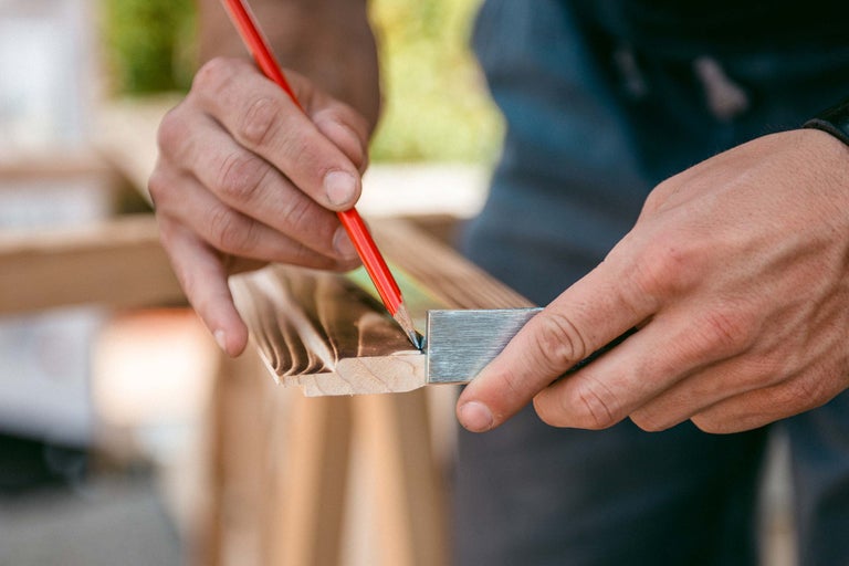 Handwerker markiert Holzleiste mit Bleistift und Winkel