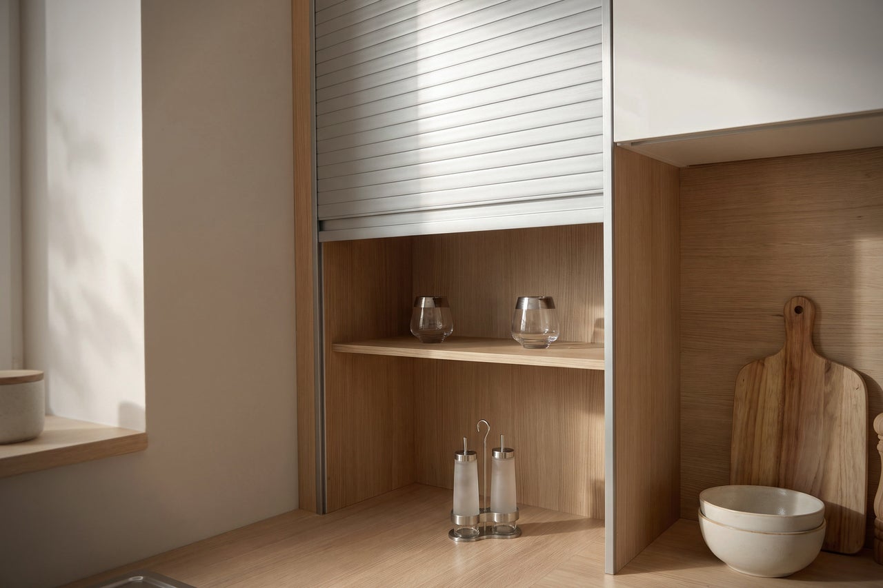 Armoire de cuisine avec rideau en imitation bois dans une cuisine moderne avec ustensiles sur le plan de travail.