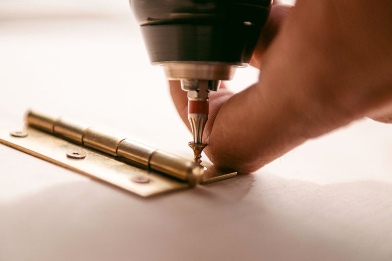 Ein Mann befestigt ein Scharnier mit einem Schraubenzieher