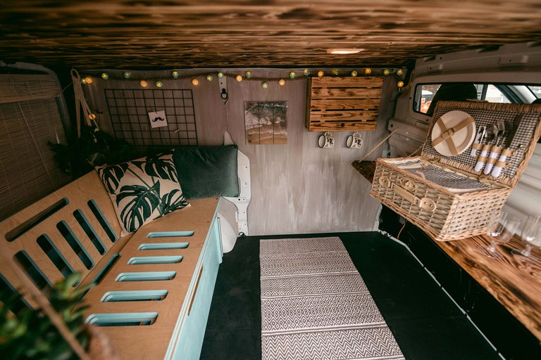 Innenausbau eines Lieferwagens mit Holzboden, Sitzgelegenheiten und Picknickkorb