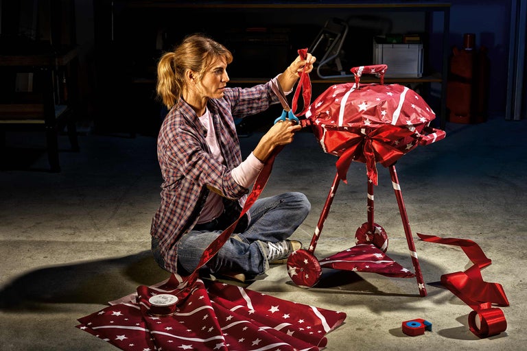 Femme décorant un gril avec du papier cadeau et un ruban