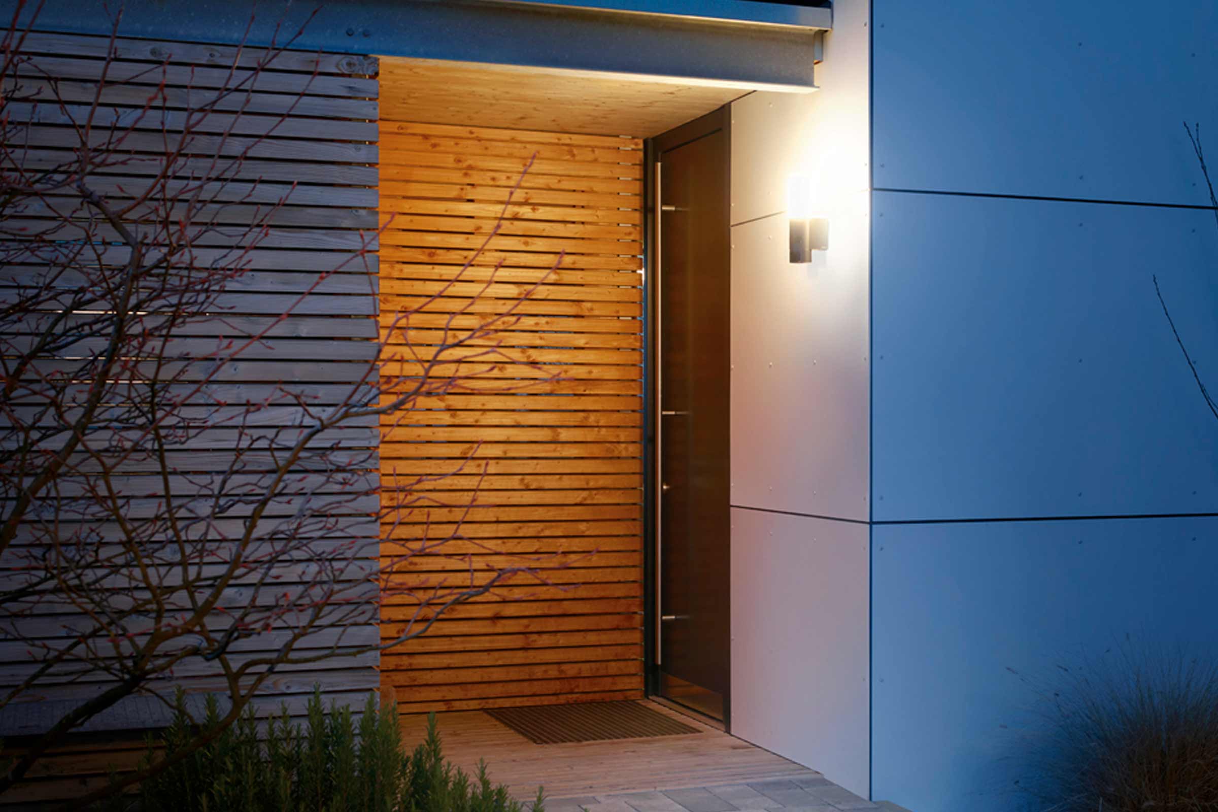 Façade de maison moderne avec éléments en bois et applique murale extérieure près de l'entrée